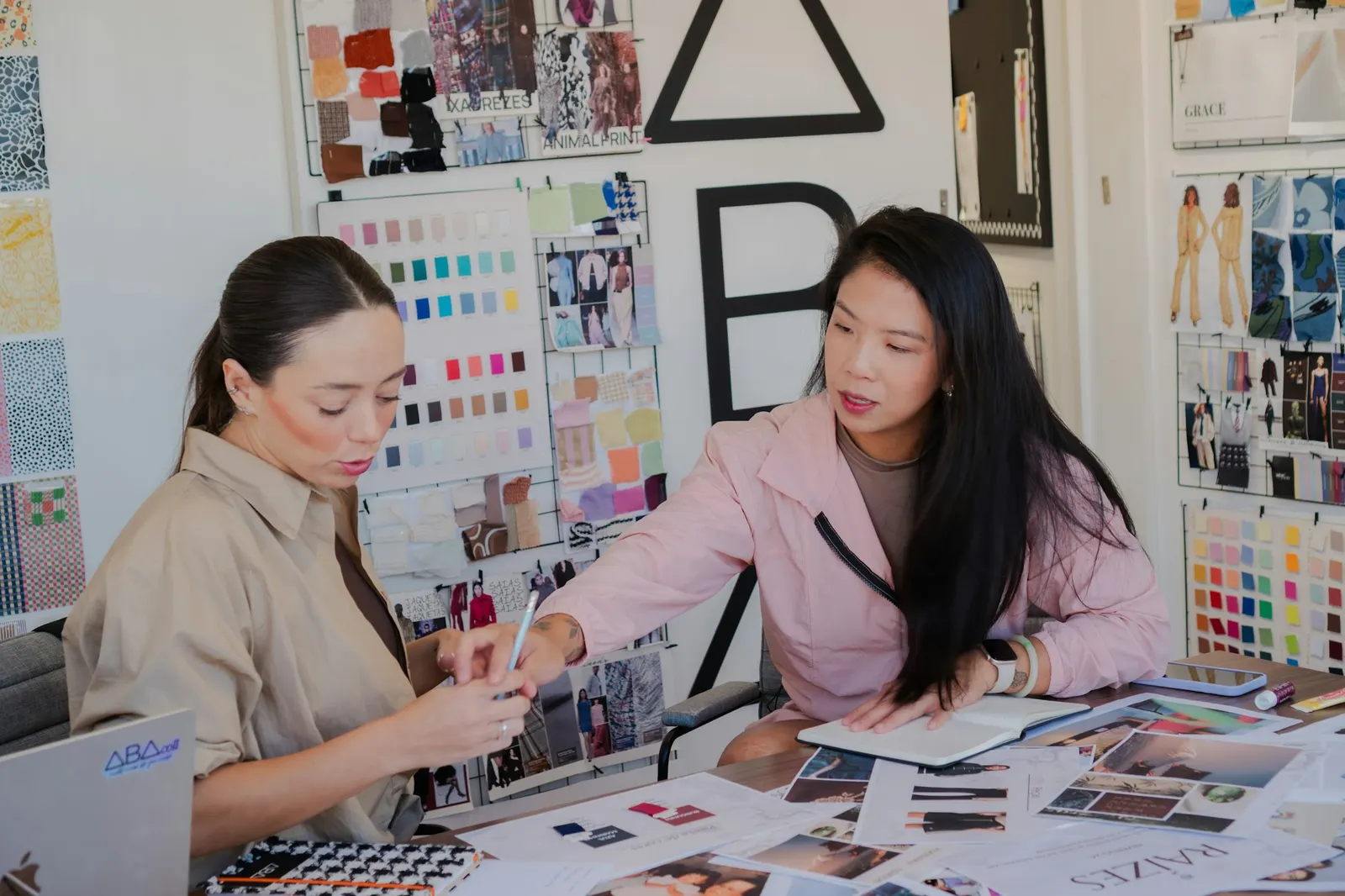 Two designers reviewing color swatches, mood boards, and printed layouts at a studio worktable