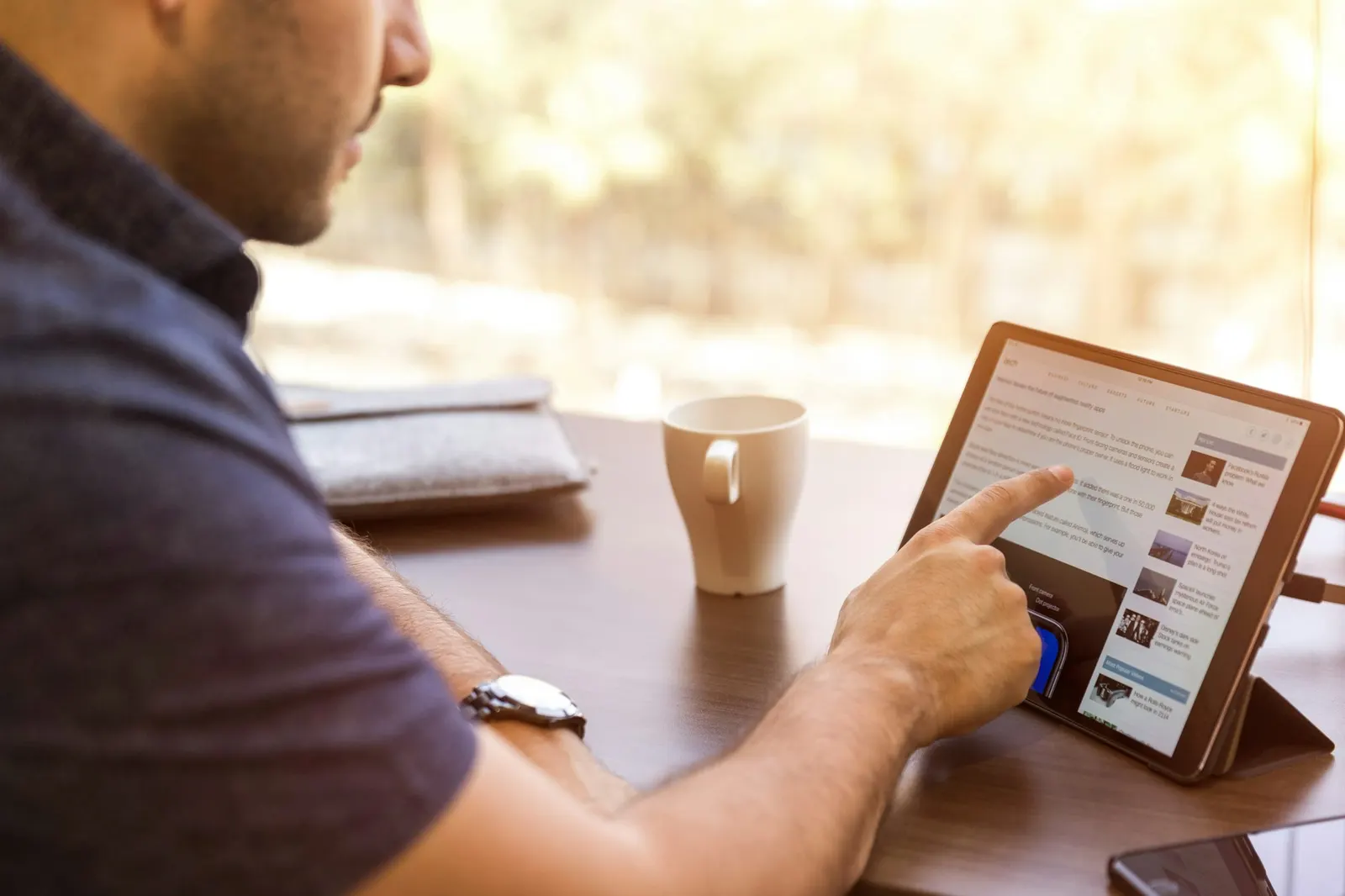 A reader browsing a news site on a tablet at a cafe table