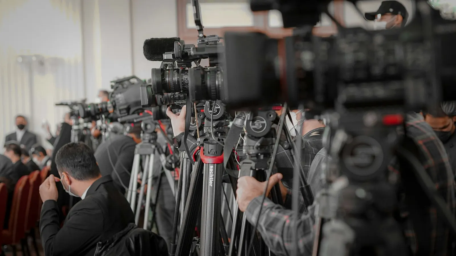 Broadcast camera operators and journalists covering a press event